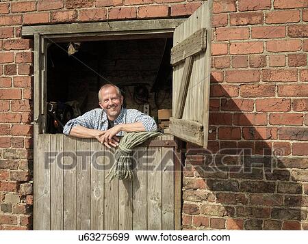 "Portrait of farmer looking out from barn door, smiling" View Large Photo Image Stock Photo - "Portrait of farmer looking out from barn door, smiling". Fotosearch