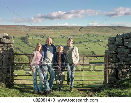 Stock Image - Portrait of farming family in front of gate in rural landscape. Fotosearch