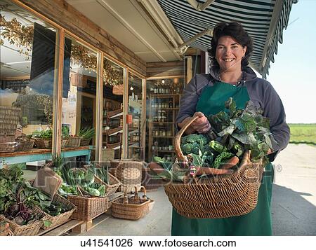 Portrait of female organic farmer with basket of organic vegetables outside farm shop View Large Photo Image Stock Photograph - Portrait of female organic farmer with basket of organic vegetables outside farm shop. Fotosearch