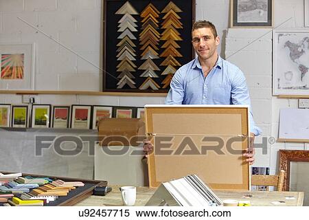 Portrait of framer holding finished picture in picture framers workshop View Large Photo Image Stock Photography - Portrait of framer holding finished picture in picture framers workshop. Fotosearch