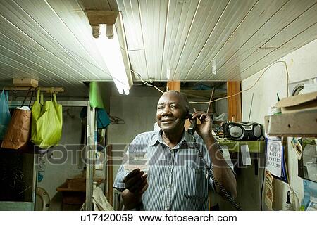 Stock Photo - Portrait of man talking on telephone in workshop. Fotosearch