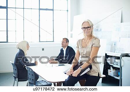 Portrait of mature businesswoman sitting on office desk View Large Photo Image Stock Image - Portrait of mature businesswoman sitting on office desk. Fotosearch