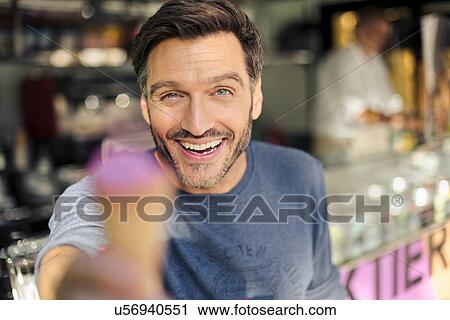 Portrait of mature man holding up ice cream cone View Large Photo Image Stock Image - Portrait of mature man holding up ice cream cone. Fotosearch