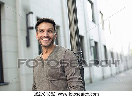 Stock Image - Portrait of mature man leaning against lamppost. Fotosearch