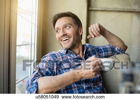 Stock Photo - Portrait of mature man looking out of window in cafe. Fotosearch