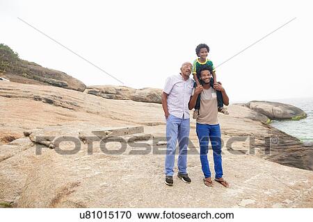 Stock Image - "Portrait of mid adult man with father and son on Ipanema beach, Rio De Janeiro, Brazil". Fotosearch