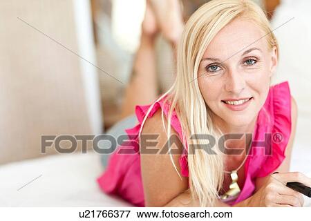 Stock Photo - "Portrait of mid adult woman, lying on bed". Fotosearch