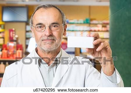 Portrait of pharmacist holding up medicine in pharmacy View Large Photo Image Stock Photography - Portrait of pharmacist holding up medicine in pharmacy. Fotosearch