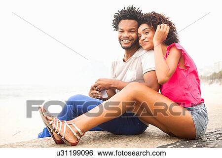 Stock Photograph - "Portrait of romantic couple sitting, Ipanema beach, Rio De Janeiro, Brazil". Fotosearch