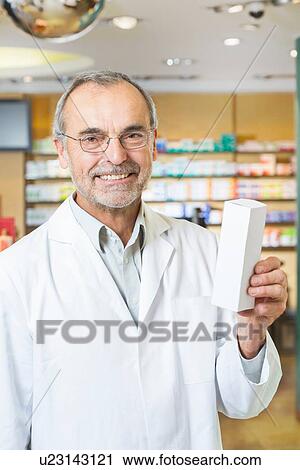 Portrait of senior male pharmacist holding up medicine in pharmacy View Large Photo Image Stock Image - Portrait of senior male pharmacist holding up medicine in pharmacy. Fotosearch