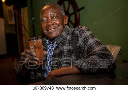 Stock Image - "Portrait of senior man drinking cocktail in bar, Rio De Janeiro, Brazil". Fotosearch