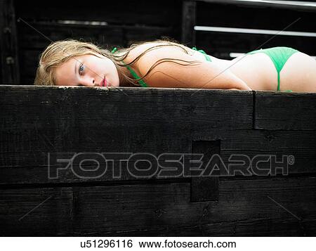 Stock Photograph - Portrait of teenage girl wearing bikini lying on pier. Fotosearch