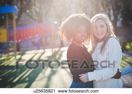Portrait of two female friends hugging in park View Large Photo Image Stock Image - Portrait of two female friends hugging in park. Fotosearch
