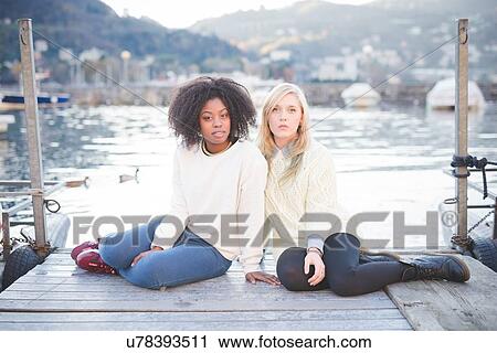 "Portrait of two female friends sitting on pier, Lake Como, Italy" View Large Photo Image Stock Image - "Portrait of two female friends sitting on pier, Lake Como, Italy". Fotosearch