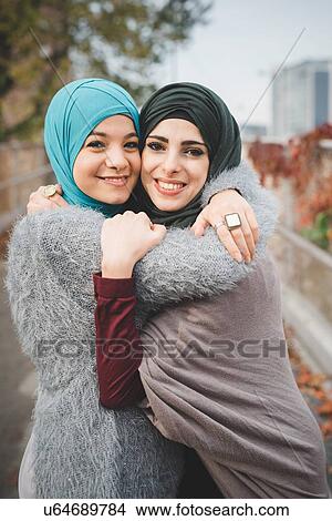 Portrait of two young female friends hugging on park path View Large Photo Image Picture - Portrait of two young female friends hugging on park path. Fotosearch