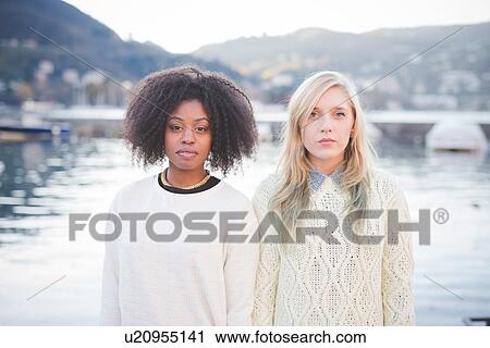 Stock Image - "Portrait of two young female friends at lakeside, Lake Como, Italy". Fotosearch