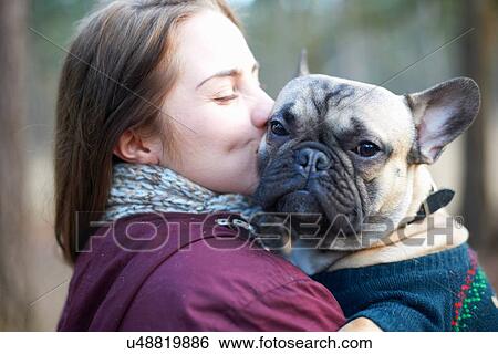 Stock Photograph - Portrait of wise dog being carried through forest by young woman. Fotosearch