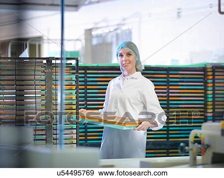 Stock Photo - Portrait of worker stacking moulds in chocolate factory. Fotosearch