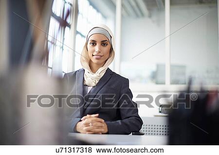 Stock Photo - Portrait of young businesswoman wearing hijab at office desk. Fotosearch