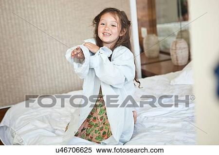 Portrait of young girl sitting on bed wearing oversized white shirt View Large Photo Image Stock Photography - Portrait of young girl sitting on bed wearing oversized white shirt. Fotosearch