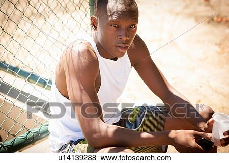 Stock Photo - Portrait of young male basketball player with smartphone and drinking water. Fotosearch