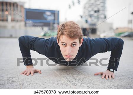 Portrait of young male runner doing push ups in city square View Large Photo Image Stock Photo - Portrait of young male runner doing push ups in city square. Fotosearch