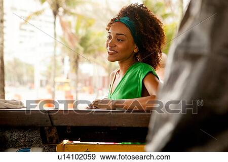 Stock Photo - "Portrait of young woman at beach bar, Ipanema beach, Rio De Janeiro, Brazil". Fotosearch