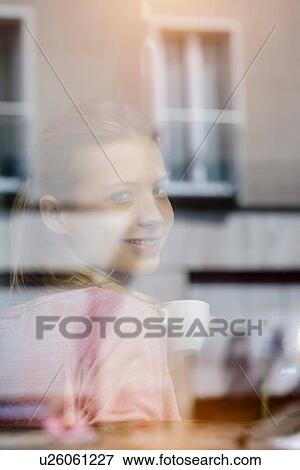 Portrait of young woman drinking coffee looking through cafe window View Large Photo Image Stock Photo - Portrait of young woman drinking coffee looking through cafe window. Fotosearch