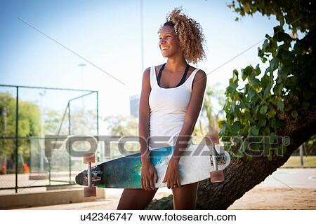 Portrait of young woman holding skateboard View Large Photo Image Stock Photo - Portrait of young woman holding skateboard. Fotosearch