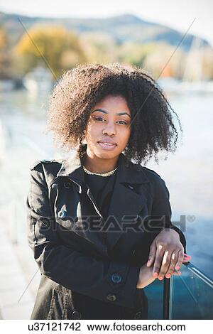 Portrait of young woman leaning against park railings View Large Photo Image Stock Image - Portrait of young woman leaning against park railings. Fotosearch