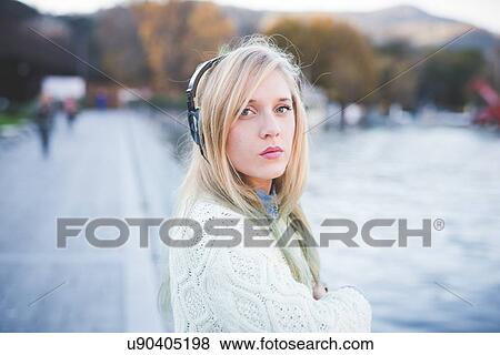 "Portrait of young woman listening to headphones on lakeside, Como, Italy" View Large Photo Image Stock Photo - "Portrait of young woman listening to headphones on lakeside, Como, Italy". Fotosearch