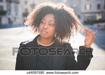 Portrait of young woman looking away in town square View Large Photo Image Stock Image - Portrait of young woman looking away in town square. Fotosearch