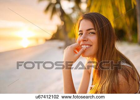Stock Image - "Portrait of young woman on Anda beach at sunset, Bohol Province, Philippines". Fotosearch