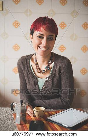 Stock Photo - "Portrait of young woman sitting at table, drinking coffee". Fotosearch