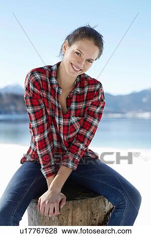 "Portrait of young woman sitting on lakeside tree stump, German Alps, Germany" View Large Photo Image Stock Photo - "Portrait of young woman sitting on lakeside tree stump, German Alps, Germany". Fotosearch