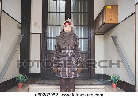 "Portrait of young woman standing in doorway, wearing winter clothes" View Large Photo Image Stock Image - "Portrait of young woman standing in doorway, wearing winter clothes". Fotosearch