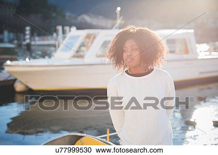 Stock Image - "Portrait of young woman standing on lakeside, Lake Como, Italy". Fotosearch