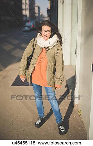 Stock Photo - Portrait of young woman sticking out tongue on street. Fotosearch