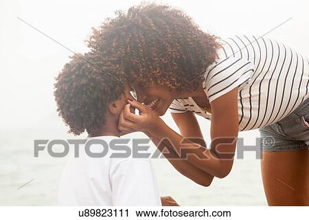 Stock Image - "Portrait of young woman touching sons cheeks on Ipanema beach, Rio De Janeiro, Brazil". Fotosearch