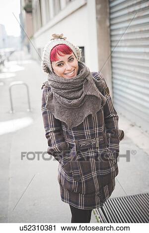 Stock Image - "Portrait of young woman walking down street, wearing winter clothes". Fotosearch