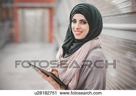 Portrait of young woman wearing hijab using digital tablet on footbridge View Large Photo Image Stock Image - Portrait of young woman wearing hijab using digital tablet on footbridge. Fotosearch