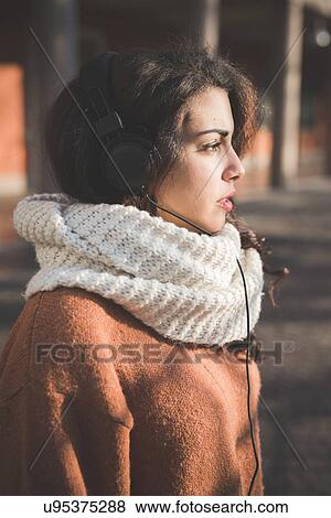 Portrait of young woman wearing headphones in park View Large Photo Image Stock Photo - Portrait of young woman wearing headphones in park. Fotosearch