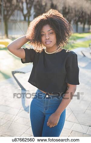 Portrait of young woman with hand in hair in park View Large Photo Image Stock Image - Portrait of young woman with hand in hair in park. Fotosearch