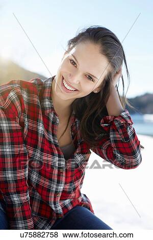 Stock Photo - "Portrait of young woman with hand in hair at snow covered lakeside, German Alps, Germany". Fotosearch