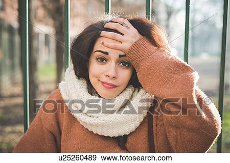 Portrait of young woman with hand on forehead in park View Large Photo Image Stock Photo - Portrait of young woman with hand on forehead in park. Fotosearch