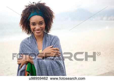 Stock Image - "Portrait of young woman wrapped in blanket on Ipanema beach, Rio De Janeiro, Brazil". Fotosearch