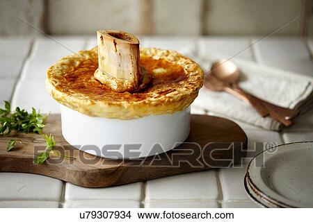 Picture - Pot pie and herbs on chopping board. Fotosearch
