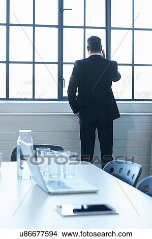Picture - Rear view of business man chatting on smartphone in conference room. Fotosearch