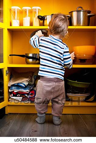 Rear view of male toddler with saucepan lid in kitchen View Large Photo Image Stock Photo - Rear view of male toddler with saucepan lid in kitchen. Fotosearch