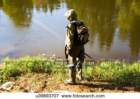 Stock Photo - "Rear view of mid adult man fishing from riverbank, Sarsy village, Sverdlovsk Region, Russia". Fotosearch